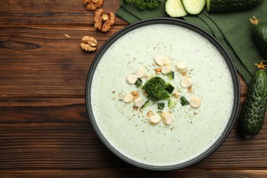Photo of Tasty cucumber soup with croutons and broccoli on wooden table, flat lay