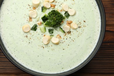 Photo of Tasty cucumber soup with croutons and broccoli on wooden table, top view
