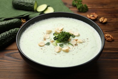 Photo of Tasty cucumber soup with croutons and broccoli on wooden table, closeup