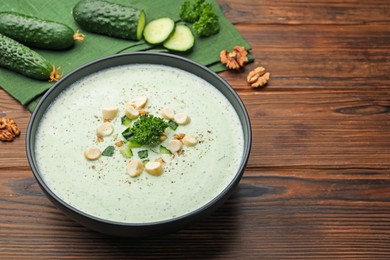 Photo of Tasty cucumber soup with croutons and broccoli on wooden table, closeup. Space for text
