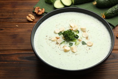 Photo of Tasty cucumber soup with croutons and broccoli on wooden table, closeup