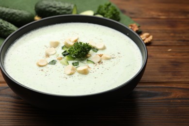 Photo of Tasty cucumber soup with croutons and broccoli on wooden table, closeup