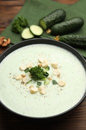 Photo of Tasty cucumber soup with croutons and broccoli on wooden table, closeup