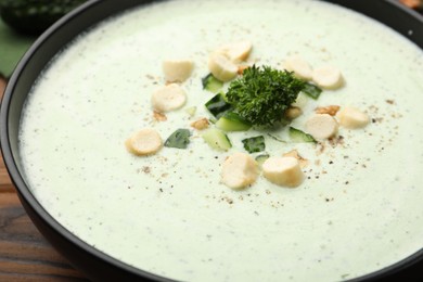 Photo of Tasty cucumber soup with croutons and broccoli on wooden table, closeup