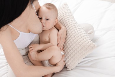 Photo of Mother breastfeeding her little baby on bed, above view
