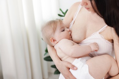 Photo of Mother breastfeeding her cute little baby indoors, closeup. Space for text