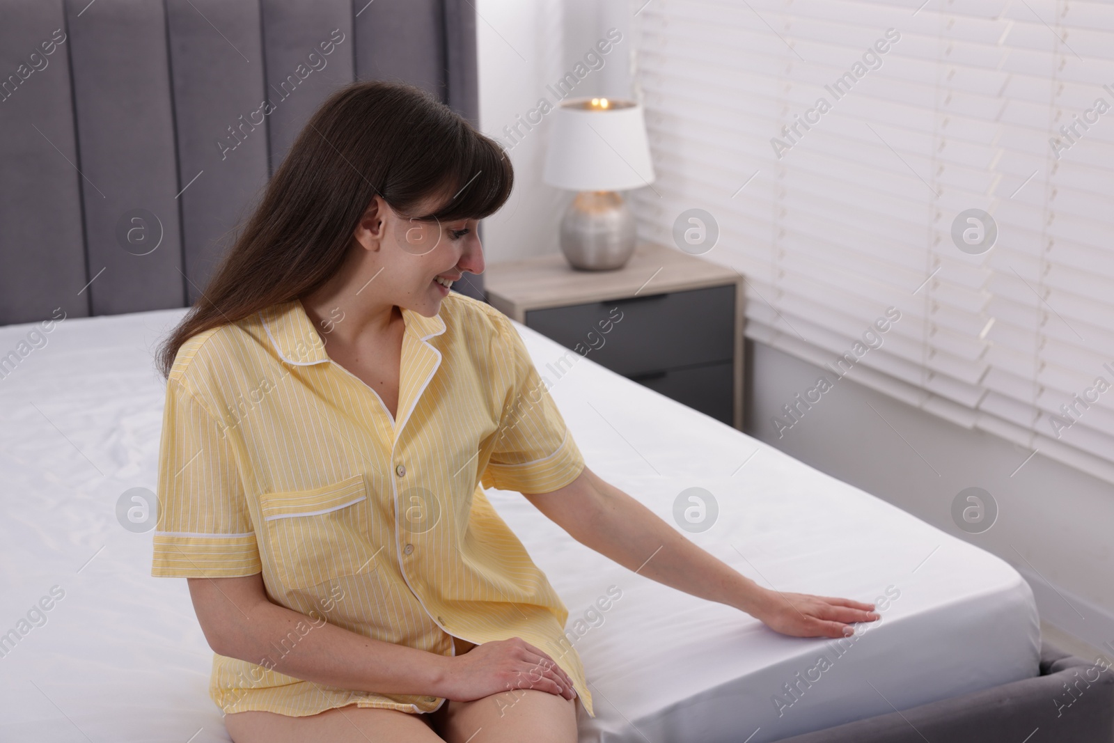 Beautiful woman sitting on soft mattress at home Photo of Beautiful woman sitting on soft mattress at home