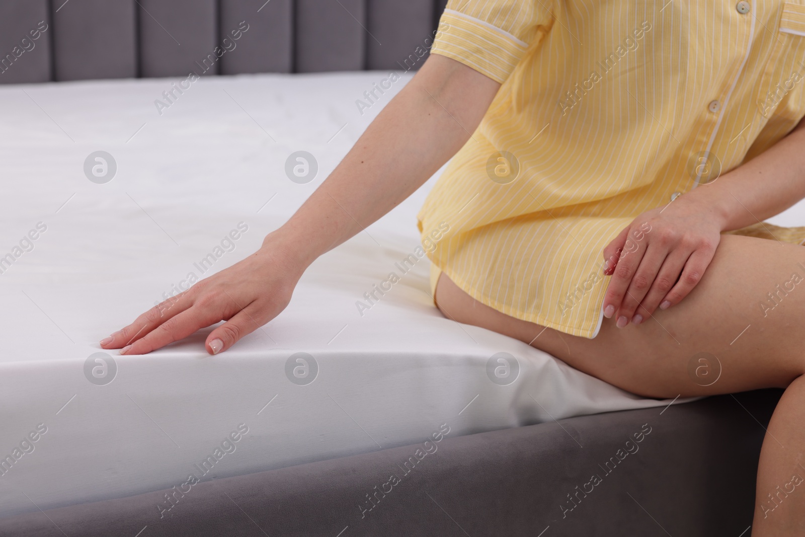 Woman touching soft mattress on bed indoors, closeup Photo of Woman touching soft mattress on bed indoors, closeup