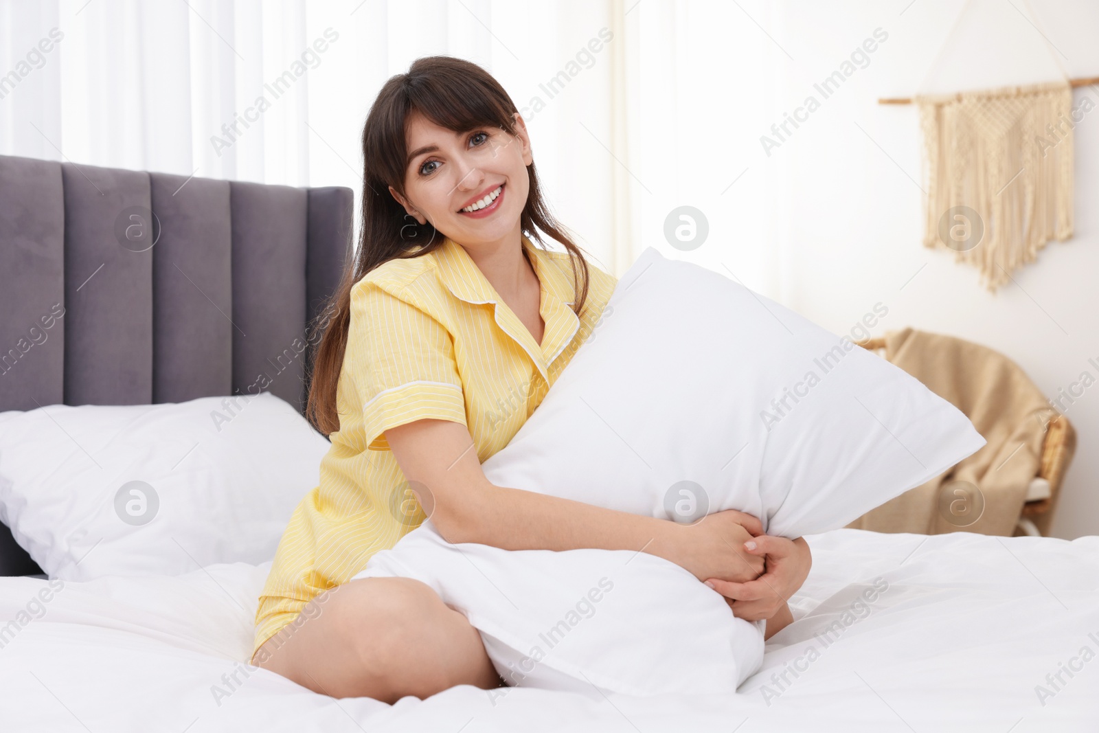 Beautiful woman with pillow on bed at home Photo of Beautiful woman with pillow on bed at home