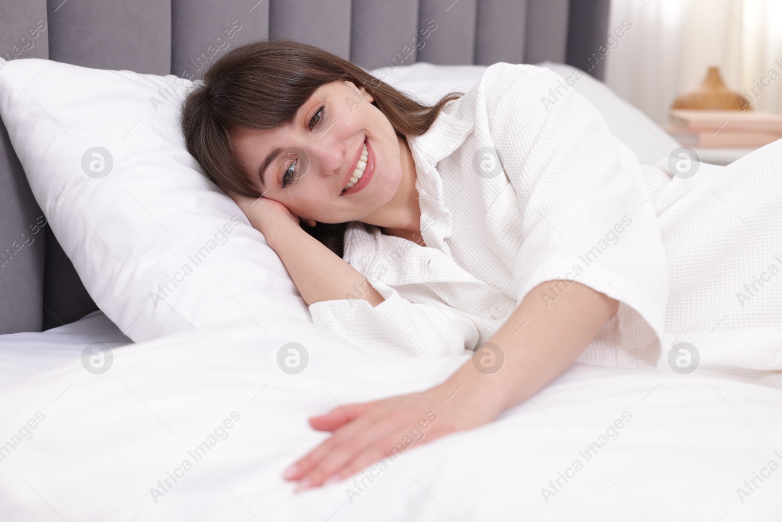 Smiling woman lying on bed at home Photo of Smiling woman lying on bed at home