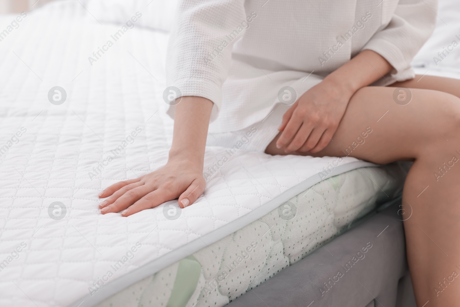 Woman touching soft mattress on bed indoors, closeup Photo of Woman touching soft mattress on bed indoors, closeup