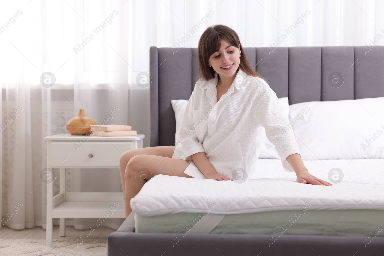 Beautiful woman sitting on soft mattress at home Photo of Beautiful woman sitting on soft mattress at home