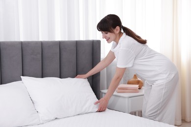 Photo of Beautiful young woman making bed at home