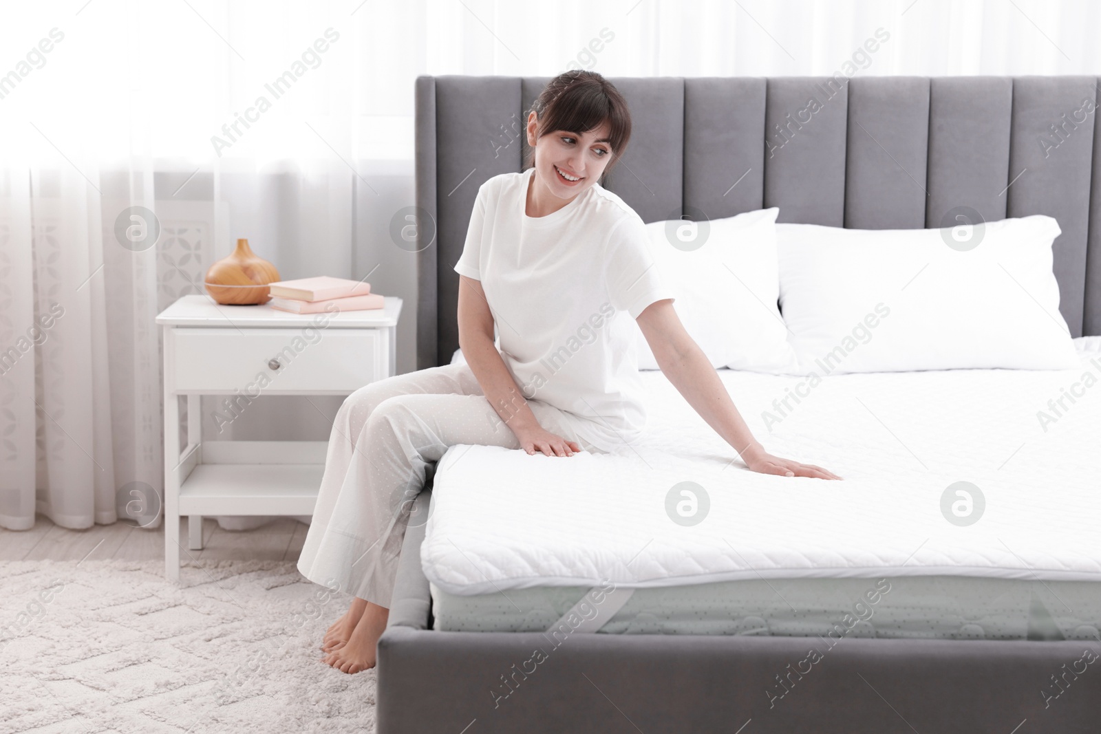 Beautiful woman sitting on soft mattress at home Photo of Beautiful woman sitting on soft mattress at home