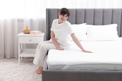Photo of Beautiful woman sitting on soft mattress at home