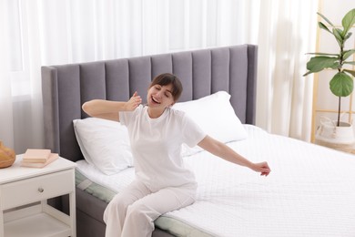 Photo of Sleepy woman yawning in bed at home