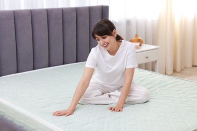 Photo of Beautiful woman sitting on soft mattress at home