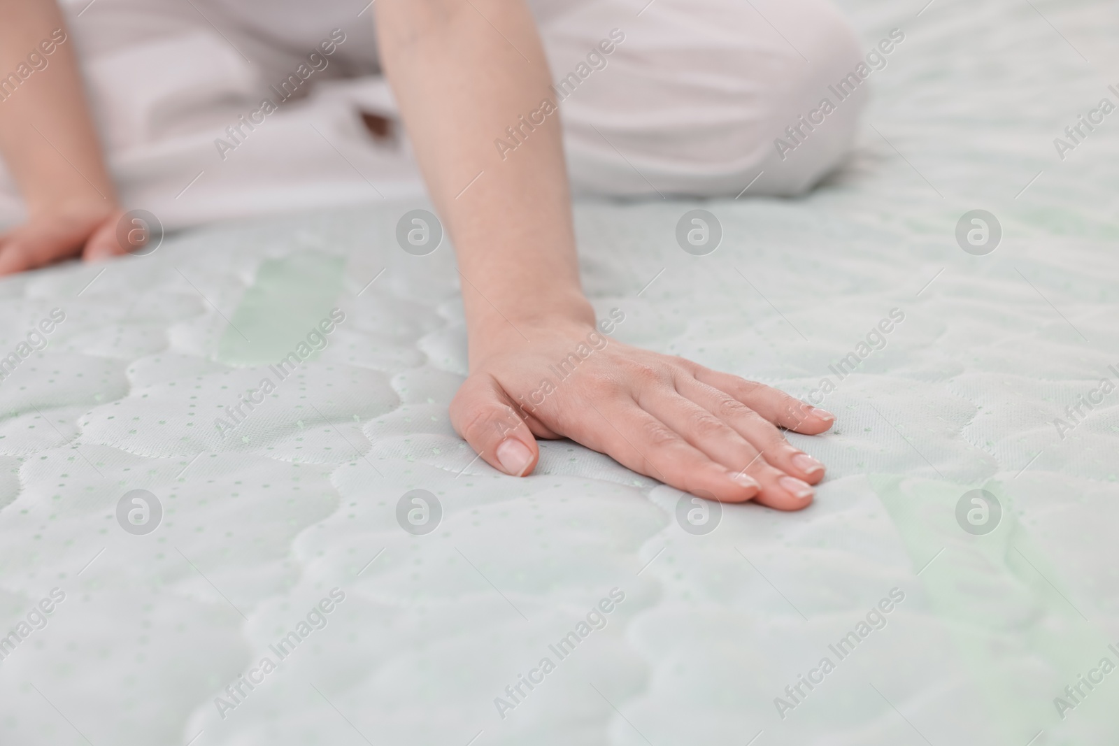 Woman touching soft mattress on bed indoors, closeup Photo of Woman touching soft mattress on bed indoors, closeup