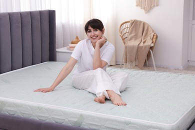Photo of Beautiful woman sitting on soft mattress at home