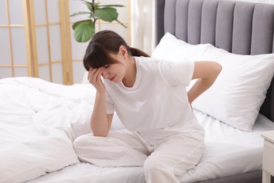 Photo of Woman suffering from back pain on bed at home