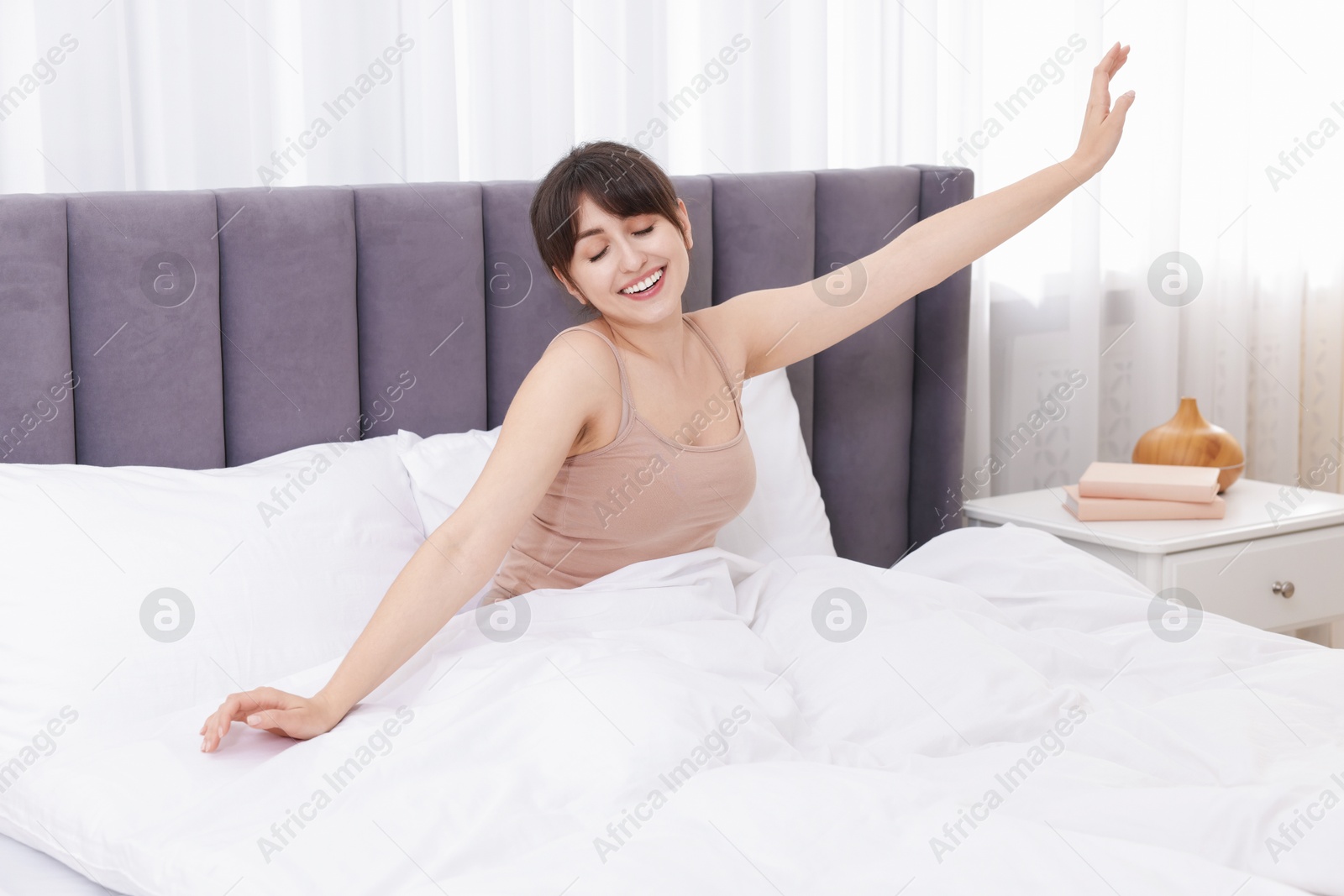 Smiling woman stretching on bed at home Photo of Smiling woman stretching on bed at home