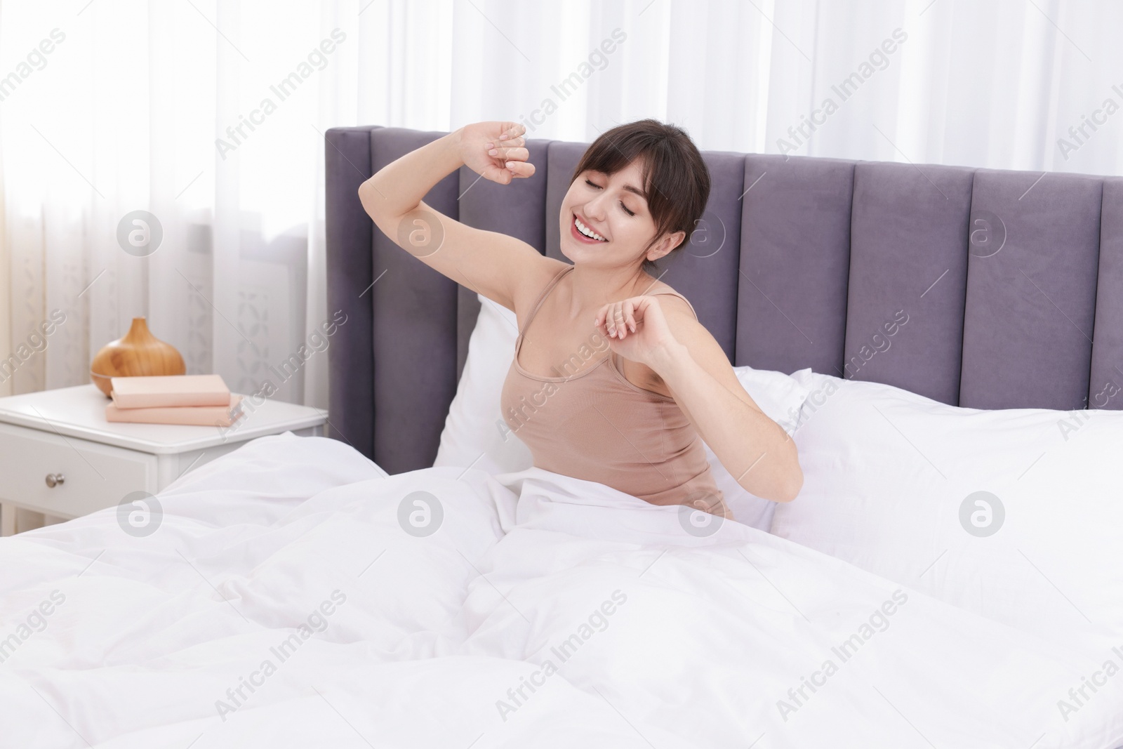 Smiling woman stretching on bed at home Photo of Smiling woman stretching on bed at home