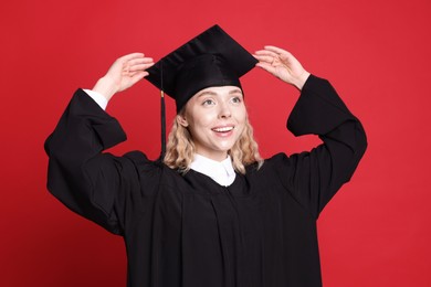 Photo of Happy student after graduation on red background