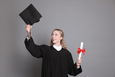 Photo of Happy student with diploma and mortarboard after graduation on grey background