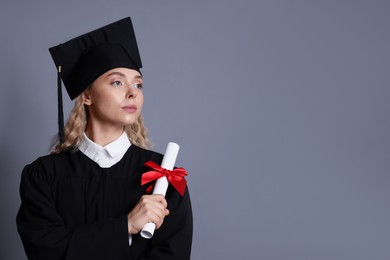 Photo of Student with diploma after graduation on grey background. Space for text