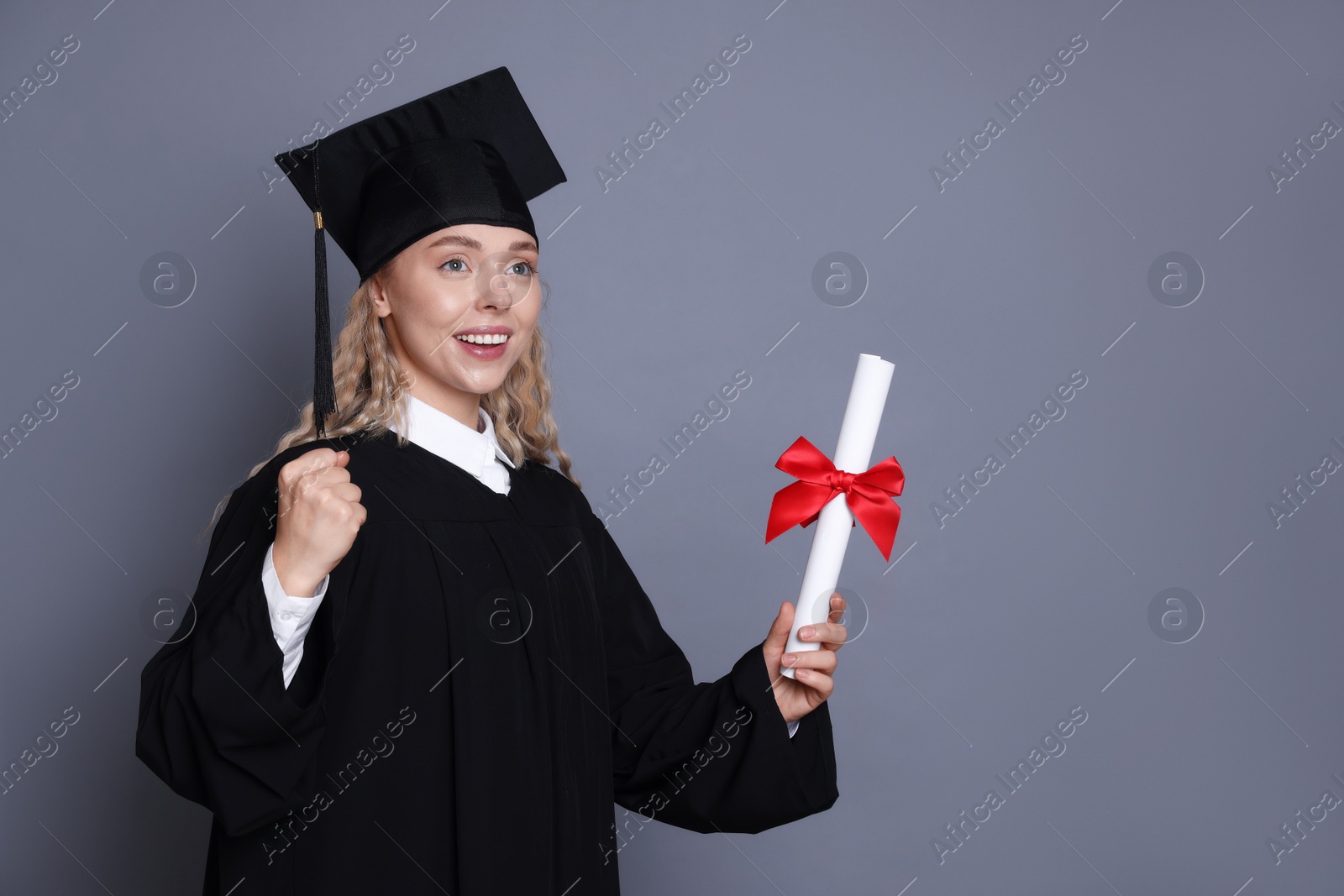 Happy student with diploma after graduation on grey background Photo of Happy student with diploma after graduation on grey background
