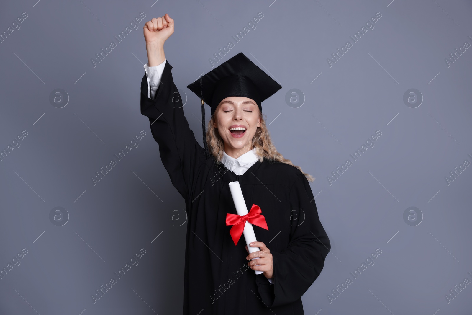 Happy student with diploma after graduation on grey background Photo of Happy student with diploma after graduation on grey background