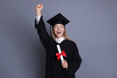 Photo of Happy student with diploma after graduation on grey background