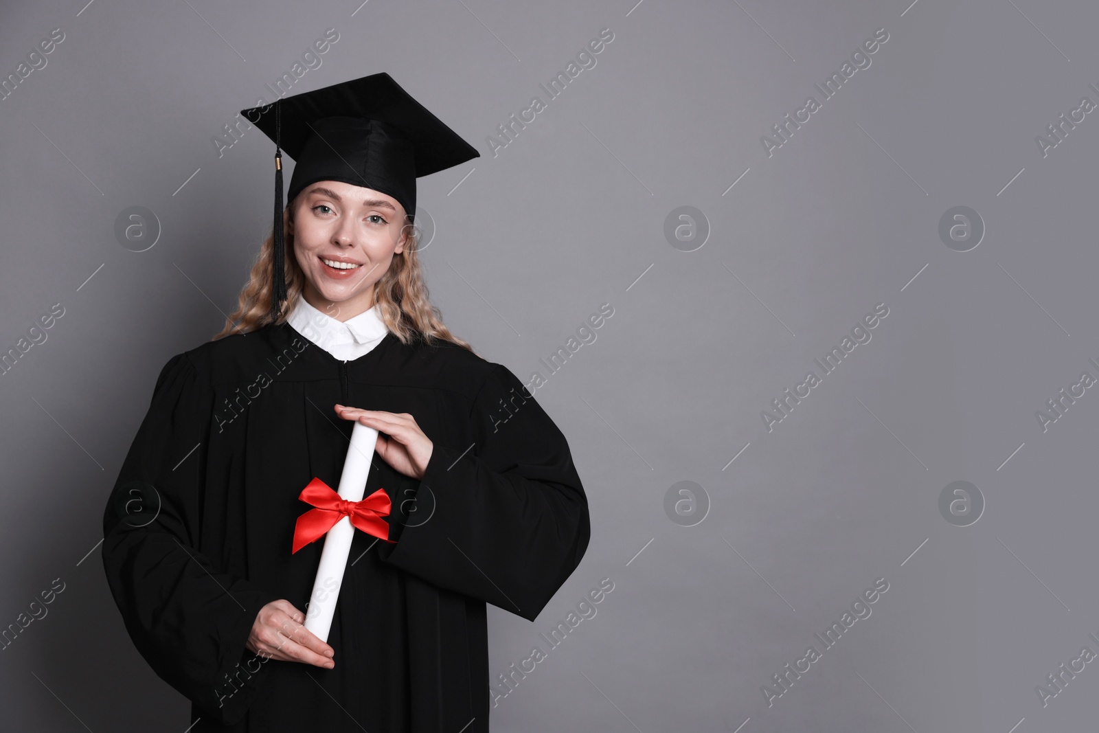 Photo of Happy student with diploma after graduation on grey background. Space for text