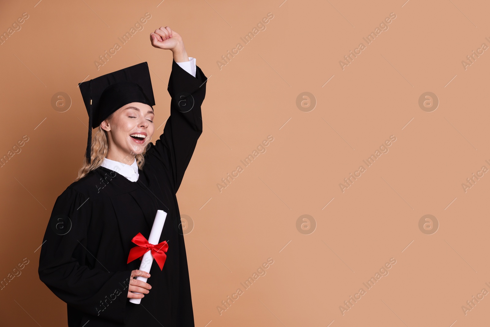 Happy student with diploma after graduation on beige background. Space for text Photo of Happy student with diploma after graduation on beige background. Space for text