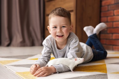 Photo of Little boy with his pet rat on floor at home