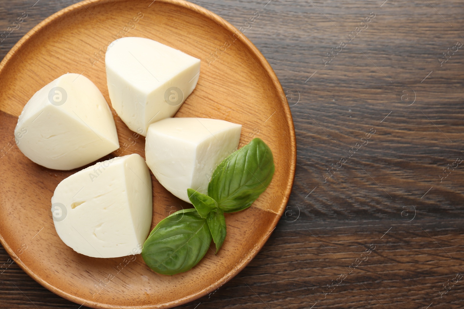Pieces of delicious mozzarella cheese and basil on wooden table, top view. Space for text Photo of Pieces of delicious mozzarella cheese and basil on wooden table, top view. Space for text