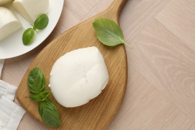Photo of Piece of delicious mozzarella cheese and basil on wooden table, flat lay. Space for text