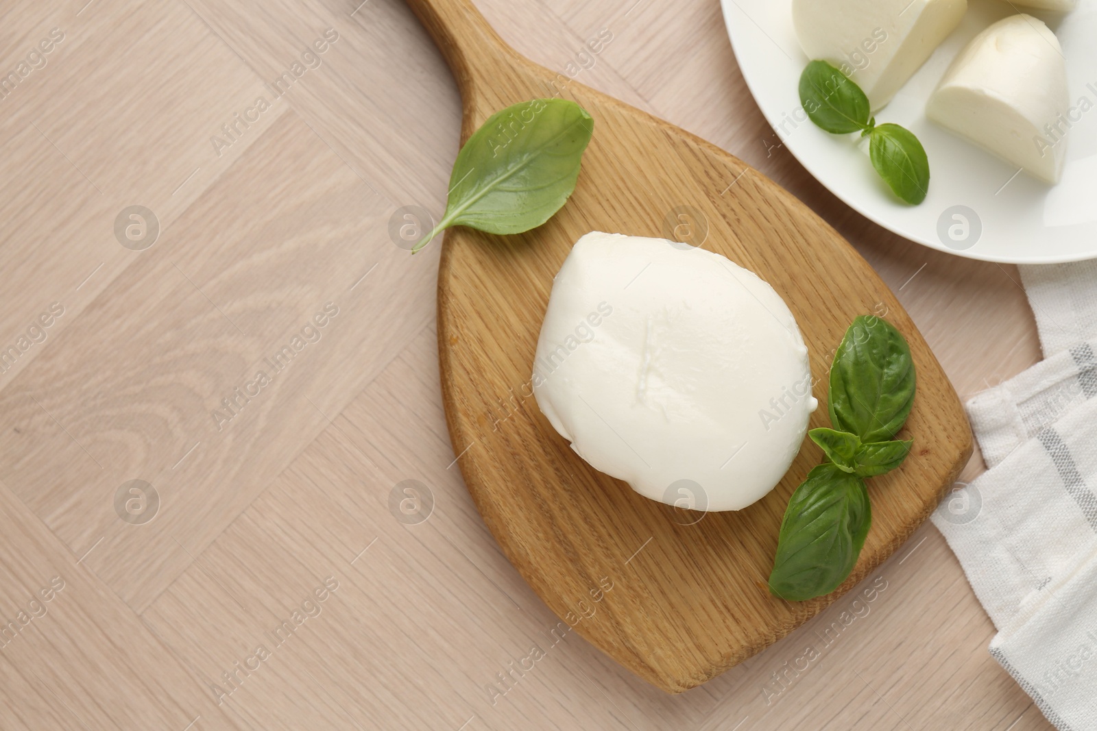 Piece of delicious mozzarella cheese and basil on wooden table, flat lay. Space for text Photo of Piece of delicious mozzarella cheese and basil on wooden table, flat lay. Space for text