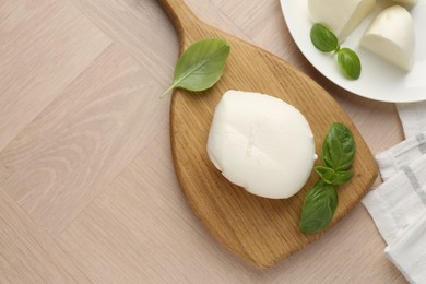 Photo of Piece of delicious mozzarella cheese and basil on wooden table, flat lay. Space for text