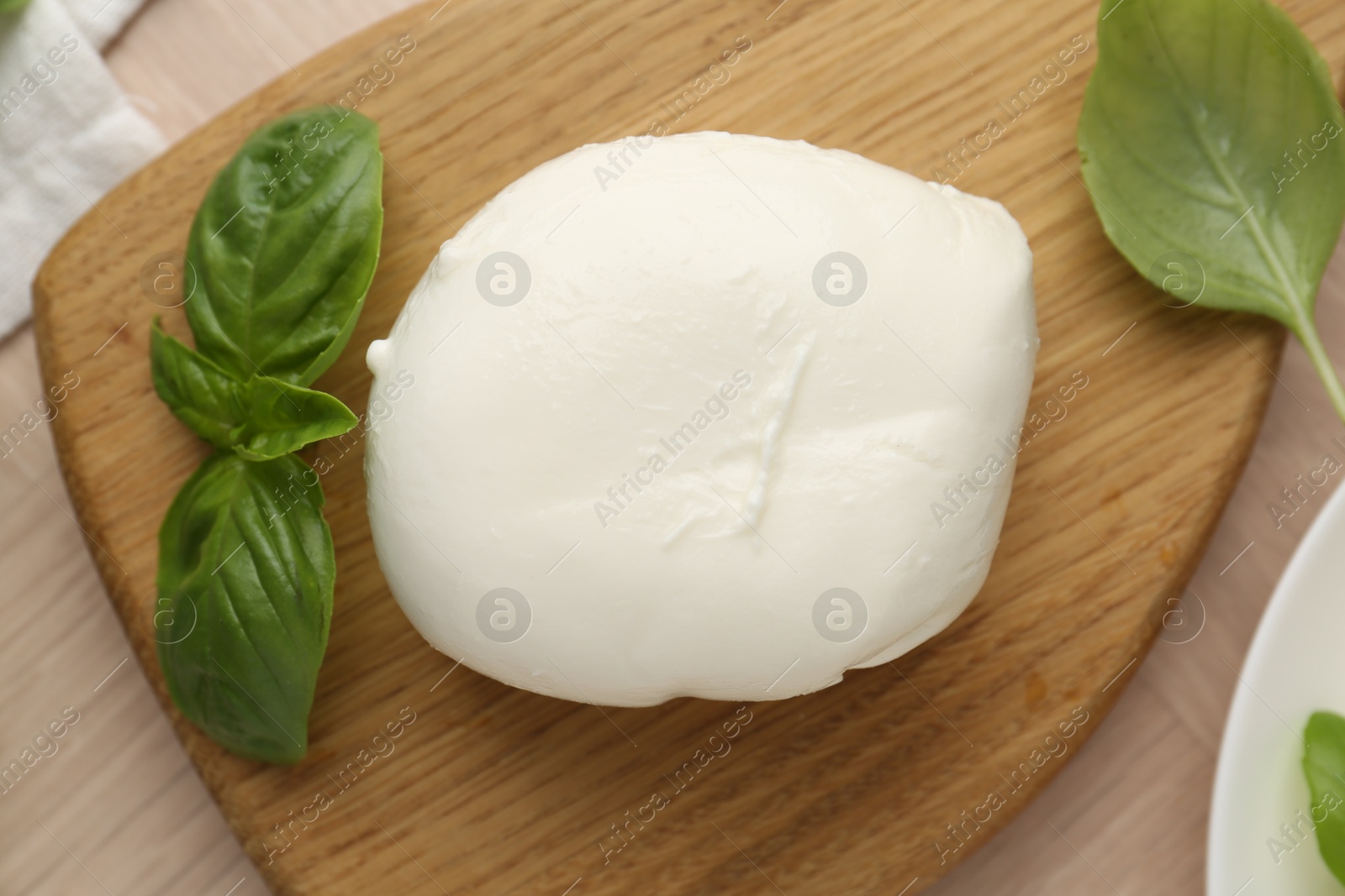 Piece of delicious mozzarella cheese and basil on wooden table, flat lay Photo of Piece of delicious mozzarella cheese and basil on wooden table, flat lay