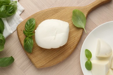 Photo of Piece of delicious mozzarella cheese and basil on wooden table, flat lay