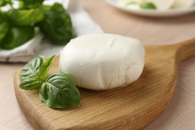Photo of Piece of delicious mozzarella cheese and basil on wooden table, closeup