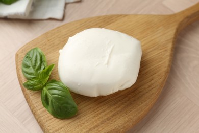Photo of Piece of delicious mozzarella cheese and basil on wooden table, closeup