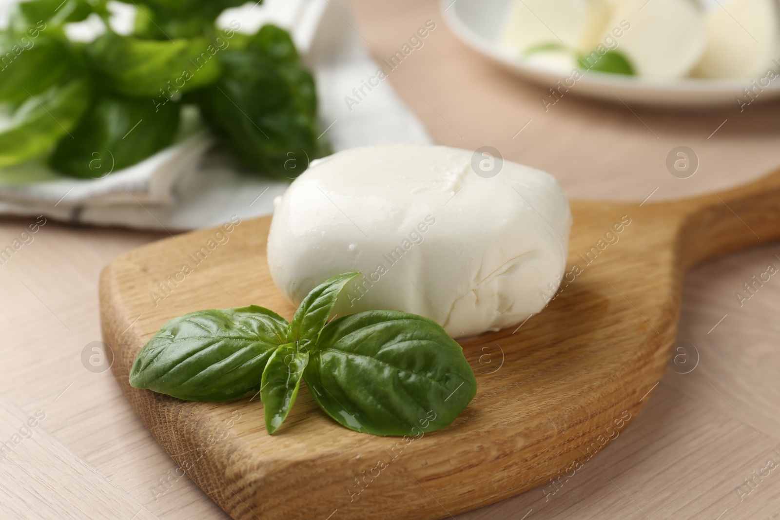 Piece of delicious mozzarella cheese and basil on wooden table, closeup Photo of Piece of delicious mozzarella cheese and basil on wooden table, closeup