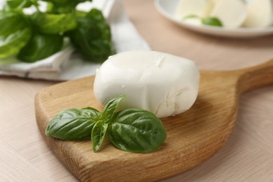 Photo of Piece of delicious mozzarella cheese and basil on wooden table, closeup