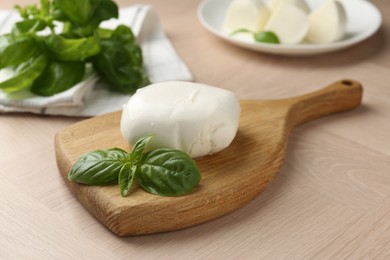 Photo of Piece of delicious mozzarella cheese and basil on wooden table, closeup