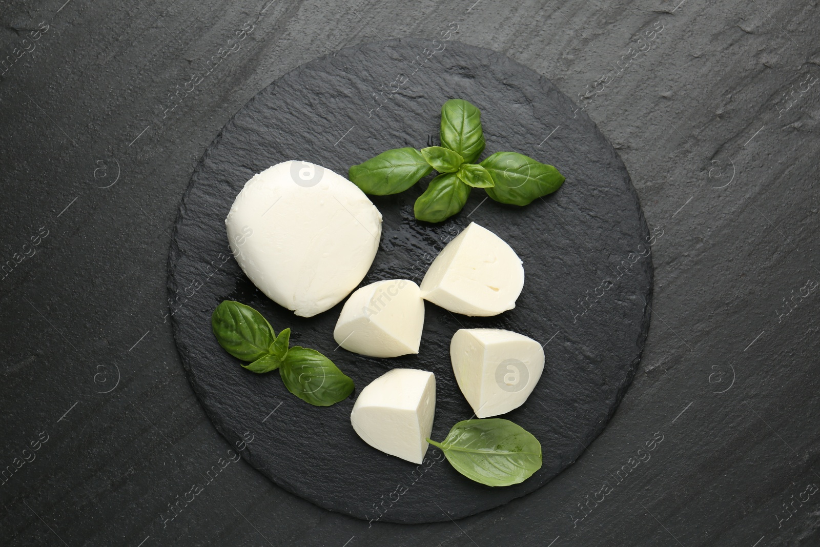 Pieces of delicious mozzarella cheese and basil on dark textured table, top view Photo of Pieces of delicious mozzarella cheese and basil on dark textured table, top view