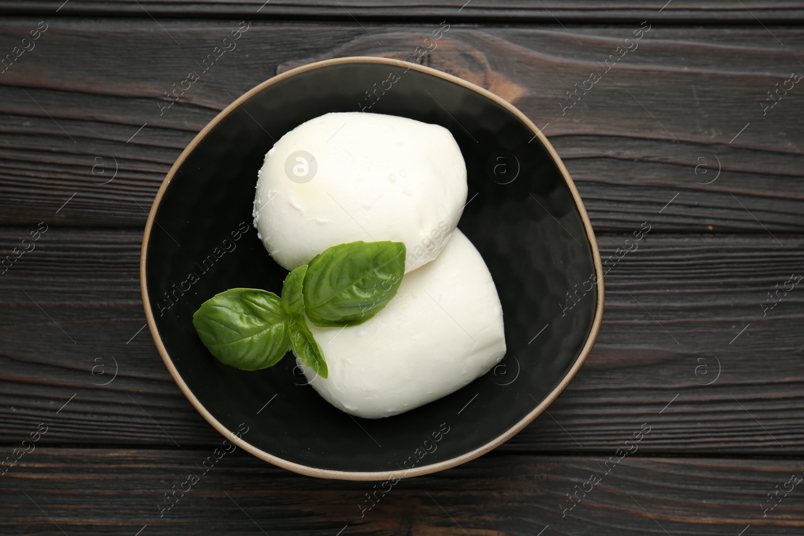Pieces of delicious mozzarella cheese and basil in bowl on wooden table, top view Photo of Pieces of delicious mozzarella cheese and basil in bowl on wooden table, top view