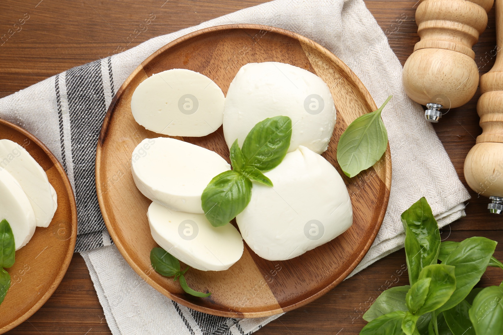 Pieces of delicious mozzarella cheese, basil leaves and shakers on wooden table, flat lay Photo of Pieces of delicious mozzarella cheese, basil leaves and shakers on wooden table, flat lay
