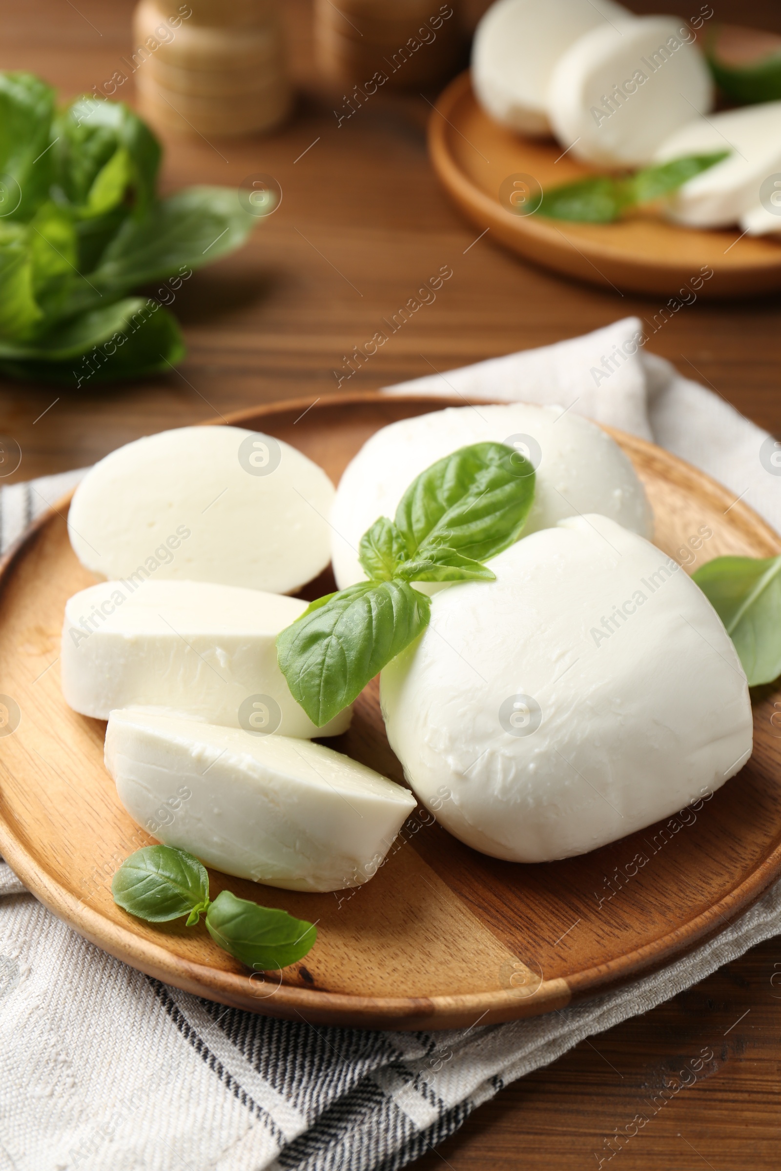 Pieces of delicious mozzarella cheese and basil leaves on wooden table, closeup Photo of Pieces of delicious mozzarella cheese and basil leaves on wooden table, closeup
